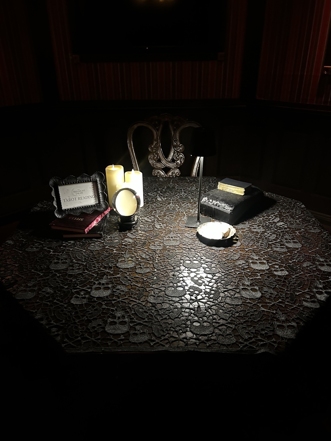 The Midnight Draw Skull & Lace reading table, with candles, cards, lighting and guest seating