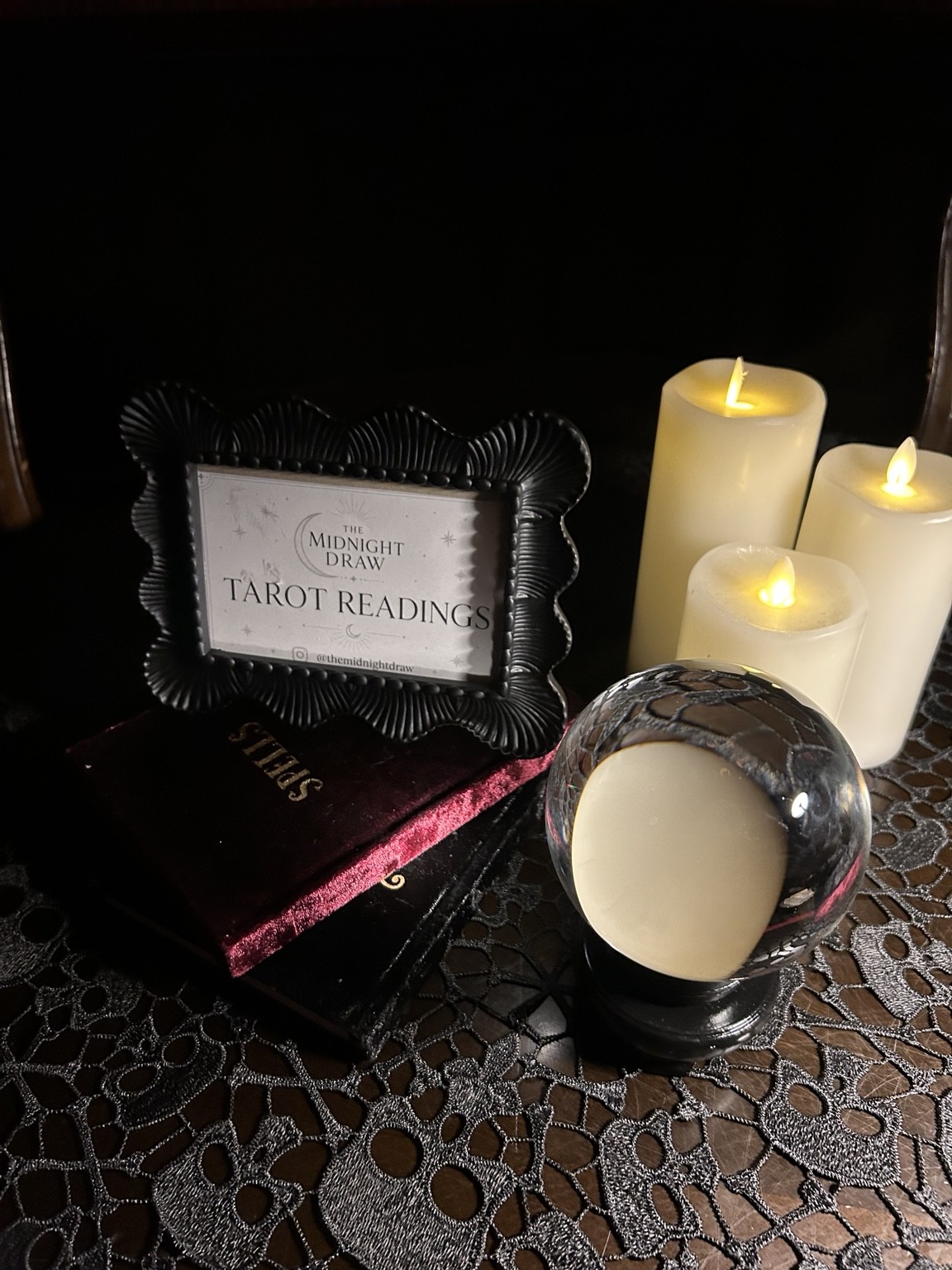 The Midnight Draw framed tarot sign, candlelight, velvet books and glass orb on skull lace